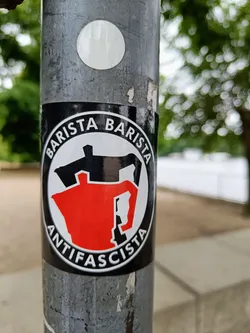 A round black and white sticker with a red coffee pot in the center. The text "BARISTA ANTIFASCISTA" is written around the coffee pot.
