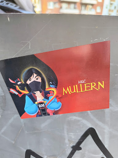 A sticker features Mulan holding a spray can, partially obscured by her disguise. The sticker is designed with a black and red background, displaying the name 'Kae Mullern'.