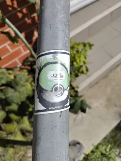 Street sticker The sticker is circular with a white border. The main design features a stylized, abstract representation of a green and grey orb, possibly a Poké Ball or a similar game element, with a black outline. Inside the orb, there is a white rectangle containing the text 'JUMP 3000' in black. Below this, in smaller text, are the words 'PARKOUR' and 'TRAMPOLIN'. The bottom edge of the sticker displays a website address: 'WWW.JUMP3000.DE'. The overall aesthetic is modern and energetic.
