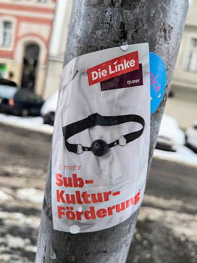 Street sticker A sticker featuring a ball gag and the text "Die Linke queer" and "Für mehr Subkulturförderung."  The sticker appears to be political in nature, promoting subculture funding by the left-wing party Die Linke.