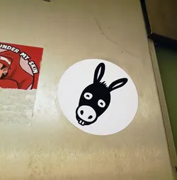 Street sticker A simple sticker of a donkey's head. The donkey is black and white and has a simple design. The sticker is round and white with a black outline.