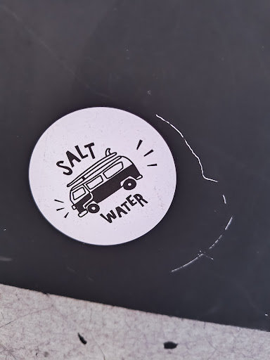 Street sticker A round sticker featuring a black and white illustration of a van with a surfboard on top, surrounded by the text "SALT WATER". The sticker has a minimalist, hand-drawn style.