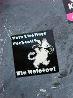 A sticker featuring a Moomin-like character holding a Molotov cocktail.  The text translates to "My favorite cocktail? A Molotov!". The sticker has a dark background with light blue and white accents. 