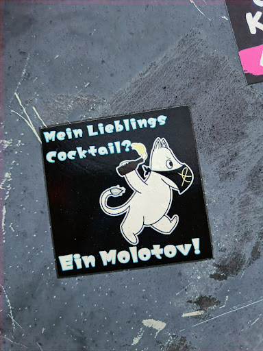 Street sticker A sticker featuring a Moomin-like character holding a Molotov cocktail.  The text translates to "My favorite cocktail? A Molotov!". The sticker has a dark background with light blue and white accents. 