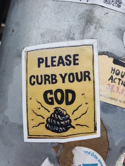 A yellow sticker with a drawing of a pile of poop and the text "Please curb your god".