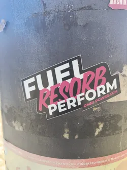 Street sticker A sticker with the text "FUEL RESORB PERFORM" is attached to a gray pole. The word "RESORB" is printed in pink.