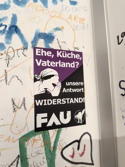 Street sticker The sticker is a purple and black rectangle with a diagonal division. The top left section is purple and displays white text in a sans-serif font that reads 'Ehe, Küche, Vaterland?' (Marriage, Kitchen, Fatherland?). The bottom right section is black. On the left side of the black section is a white silhouette of a person's head and shoulders, with their hand cupped to their mouth as if speaking or shouting. Below the silhouette, in large white sans-serif font, are the words 'WIDERSTAND!' (Resistance!). To the right of 'WIDERSTAND!', and above the FAU logo, is white text that reads 'unsere Antwort' (our answer). In the bottom right of the black section is a circular logo with a white silhouette of a cat with its back arched, and the letters 'FAU' in white block letters to the left of it.