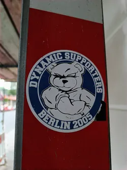 Street sticker A round sticker featuring a teddy bear with its arms crossed. The text on the sticker reads 'Dynamic Supporters Berlin 2005'.