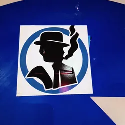 Street sticker This sticker features a stylized silhouette of a man wearing a fedora and smoking. The design is simple yet striking, with a retro feel. The man is depicted in black against a white and light-blue circular background. The sticker is neatly placed on a blue surface.