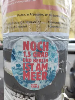 Round sticker with a blue ocean background and red text. The text says "NOCH 1,5 GRAD UND BERLIN IST AM MEER" which translates to "Only 1.5 degrees and Berlin is by the sea".  There is a small logo at the bottom that says "Klima Tak!".