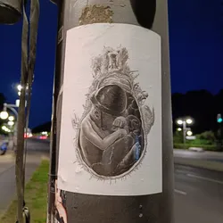 This sticker features a striking grayscale illustration of a fetus inside a womb, appearing to break free from its confines. The detail in the drawing is impressive, creating a powerful and thought-provoking image. The overall style is dark yet artistic. The sticker is displayed on a street lamp post.