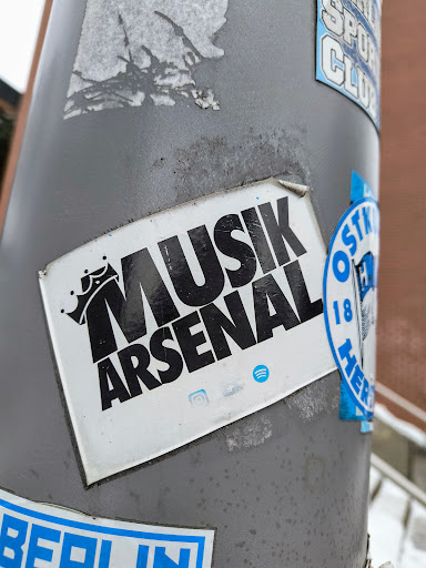 Street sticker Black and white sticker with the text Musik Arsenal and a crown graphic.  There are also small social media icons visible at the bottom.