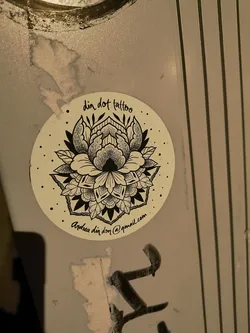 A round sticker with a detailed black and white floral design. The sticker promotes "din dot tattoo" and includes the email "Andrea.dindon@gmail.com".