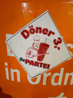 Street sticker A sticker featuring a chef preparing a döner kebab.  The text includes 'Döner 3' and 'Die PARTEI', and a website address is visible at the bottom.