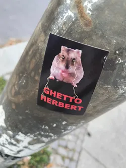 Street sticker A sticker featuring a hamster with what appears to be gold thread coming from its eyes. The text 'GHETTO HERBERT' is printed below the image of the hamster.