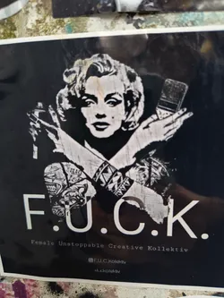 Street sticker A black and white sticker featuring a stylized image of Marilyn Monroe holding a spray can and a paintbrush in an "X" formation across her chest, with the text "F.U.C.K." above the acronym's full name, "Female Unstoppable Creative Kollektiv." Social media handles are present as well.