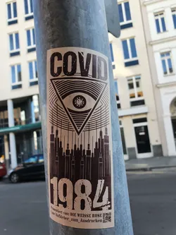 A sticker with a design combining imagery of COVID-19, an eye inside a triangle, syringes forming a cityscape, and the number 1984.  The text at the bottom indicates it's from Die Weisse Rose and provides a QR code. The overall aesthetic is dark and slightly dystopian.