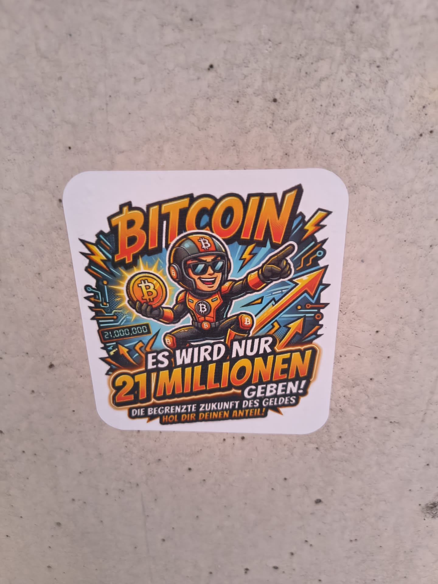 A square sticker with rounded corners depicting a cartoon mascot in a black and orange suit holding a Bitcoin. The design uses vibrant orange, yellow, and blue colors with dynamic lightning and arrow graphics. German text emphasizes the 21 million limit of Bitcoin.