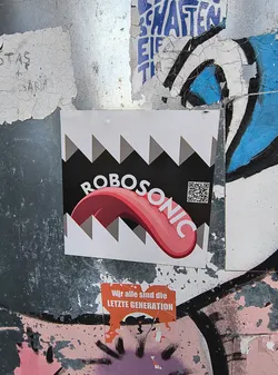 Street sticker A sticker featuring a cartoon tongue sticking out of a pair of jagged teeth, with the word Robosonic written across it.  There is also a QR code included on the sticker.