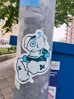Street sticker The sticker features a cartoon character resembling a Smurf, depicted with a muscular physique. The character has large, round blue eyes with glasses, a white hat, and is wearing a dark blue vest with light blue accents. The character's arms are flexed, and its legs are bent. The sticker is predominantly white with blue and dark blue outlines and details. There are also two 'X' symbols in black on the character's legs.