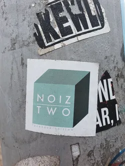 Street sticker A minimalist sticker featuring the logo of Noiz Two, a teal cube with the text 'NOIZ TWO' in a sans-serif font.  The sticker also includes a Facebook link at the bottom.