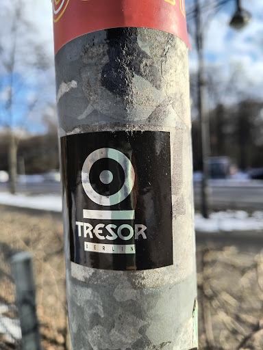 Street sticker A black sticker is affixed to a pole, displaying the logo of Tresor Berlin. The logo features a concentric circle design above the word 'TRESOR' and 'BERLIN' printed below in smaller font size.