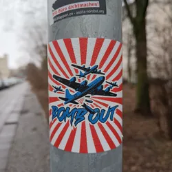 Street sticker This sticker shows a stylized image of a World War II bomber plane dropping bombs against a red and white sunburst background. The text "BOMB OUT" is prominently displayed in a graffiti-style font.  The overall aesthetic is reminiscent of vintage war propaganda posters. There are no QR codes or social media links visible on this sticker.