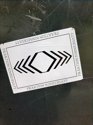 Street sticker A white square sticker with black graphic design and text. The text 'Fraktion Nimmersatt' is repeated on all four sides. The central design is a geometric pattern of arrows and hexagons.