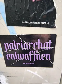 Street sticker The sticker is rectangular with a black background. Prominently displayed in the center are two lines of text in a stylized, gothic-like font, colored in a vibrant lavender. The top line reads 'patriarchat' and the bottom line reads 'entwaffnen'. Below these main lines, in smaller, white, sans-serif font, is the text 'JIN JÎYAN AZADÎ'. The sticker appears to be slightly worn and has a few thin, white lines crossing over it, possibly from tape or cracks in the surface it's adhered to.