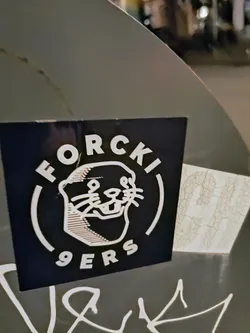 Street sticker The sticker has a dark blue background with white lettering and an otter illustration. The text reads "FORCKI 9ERS". It is placed on what appears to be a metal surface.