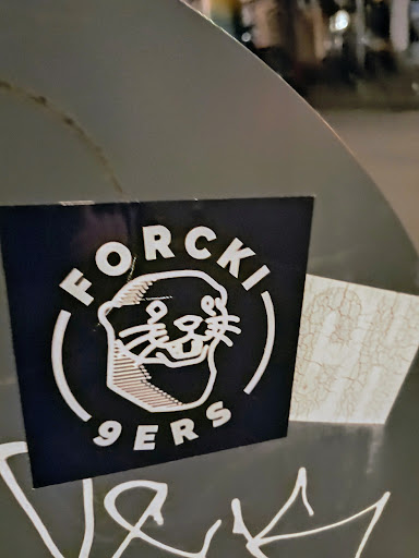 The sticker has a dark blue background with white lettering and an otter illustration. The text reads "FORCKI 9ERS". It is placed on what appears to be a metal surface.