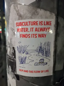 Street sticker A white sticker with red text and a simple illustration of a person on a log in a river. The text on the sticker says, "Subculture is like water, it always finds its way."  At the bottom it says, "Ulpi and the flow of life". The illustration is a simple drawing of a waterway with reeds on either side, and a figure floating on a log.