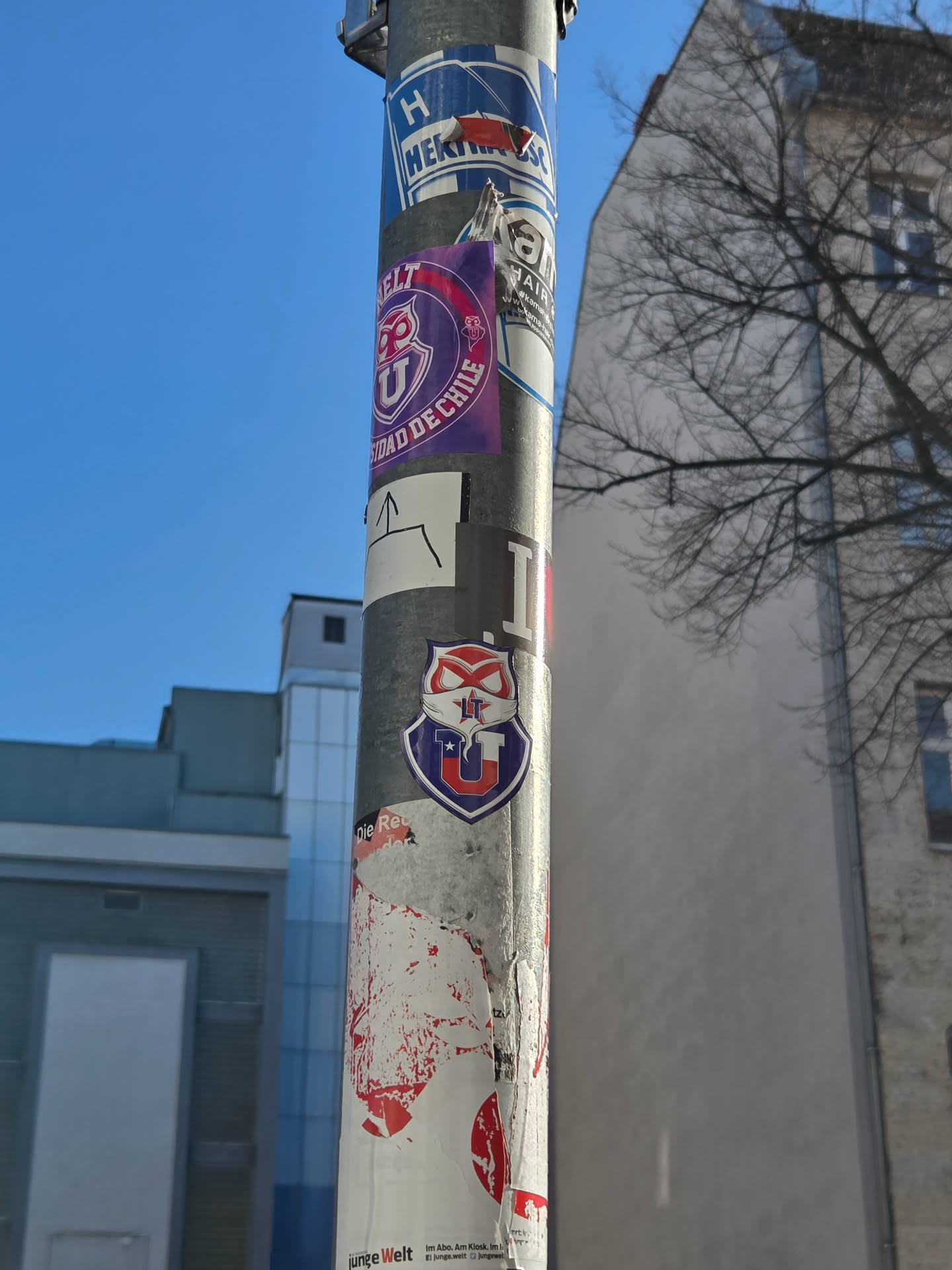 A shield-shaped sticker, predominantly blue with a white outline. It features a large, stylized white 'U' at the bottom, accented with a small red star on its left arm and another red star on the right. Above the 'U', a white and red masked figure, known as 'El Chuncho' (The Owl) mascot, is depicted with red eyes and the letters 'LT' on its forehead. The design incorporates red, white, and blue colors, reflecting the Chilean flag and the club's identity.