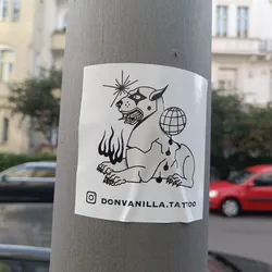 Street sticker A black and white sticker featuring an illustration of a stylized dog, possibly a lion-dog hybrid, with flames, a starburst, and a globe.  The style is reminiscent of traditional tattoo flash.  The artist's Instagram handle is included at the bottom. 