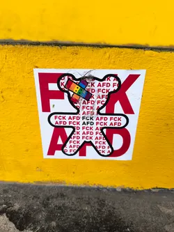 Street sticker A sticker featuring a small bear graphic in the center and the acronym FCK AFD repeated multiple times. The acronym is written in large red letters, with the bear in the middle, suggesting a protest message against something represented by AFD.
