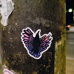 Street sticker This sticker features a stylized bird with wings that look like they are made of feathers. The colors are a gradient from pink to purple to blue, and the bird itself is black. The image is striking, and the colors are eye-catching.