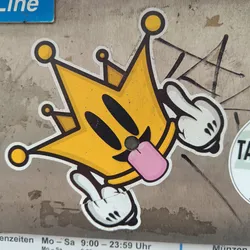 Street sticker A yellow cartoon character wearing a crown and sticking its tongue out. It has a mischievous expression and is depicted with simple, bold lines. The style is reminiscent of pop art and graffiti.