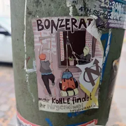 Street sticker A sticker depicting an illustration of two people climbing a ladder and lowering a backpack with the word "Bonzerat" and the phrase "More coal can be found somewhere!" The sticker also features an anarchist symbol. The website luetzerathlebt.info is mentioned at the bottom. 
