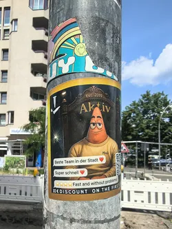 Street sticker A rectangular sticker with a gold border showing Patrick Star in a yellow sweater, sitting in an ornate chair. Includes the text 'Aktiv', German review bubbles, and a QR code.