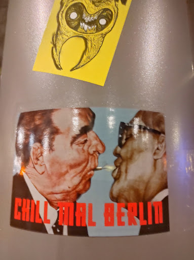 Street sticker A sticker depicting a caricature of two men, possibly historical figures, sharing a cigarette.  The background is light blue, and the text 'Chill mal Berlin' is written in red at the bottom.