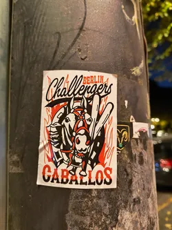 Street sticker Sticker featuring a design with two horses and a rider, set against flames. The text 'BERLIN Challengers' is at the top, and 'CABALLOS' at the bottom. The style is reminiscent of vintage sports team logos or illustrations.