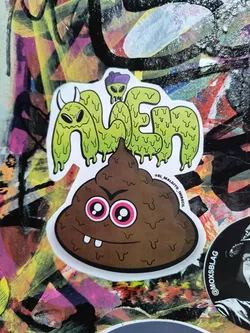 Street sticker The sticker features two main elements stacked vertically. The top element is text that spells out 'ALIEN' in a dripping, slime-like font, colored light green. Each letter is outlined in black and has a white border. At the top of the 'A', there's a small, simplified green alien wearing a purple hat. The bottom element is a brown, stylized poop emoji with a mischievous grin, featuring two prominent teeth. Its eyes are large and round with bright pink irises and white pupils, giving it an angry or mischievous expression. It also has a white border and a black outline.