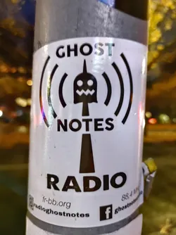 Street sticker A sticker for Ghost Notes Radio, featuring a stylized ghost-like tower emitting radio waves.  The sticker includes a website address and social media links for Facebook and Instagram.