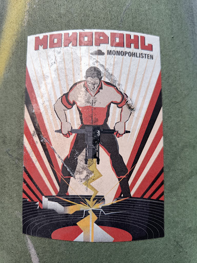 Street sticker A sticker featuring soviet-style propaganda artwork. A man is depicted using a jackhammer to destroy a vinyl record. The text \"МОНОПОЛ\" and \"MONOPOHLISTEN\" is visible. 