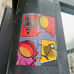 A colorful sticker featuring various cartoonish designs.  The main focus is a pink creature with a round head, accompanied by other smaller illustrations including a red creature and a fish skeleton. One speech bubble says "Rio Lovers".