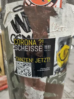 Street sticker A sticker expressing frustration with the Corona pandemic and encouraging dancing. It features a QR code and a smiley face mask.  The text says: "CORONA?! SCHEISSE!!! TANZEN! JETZT!" which translates to "Corona?! Shit!!! Dance! Now!"