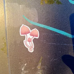A lovely sticker featuring a cluster of pink mushrooms. The artist's signature is visible at the bottom.