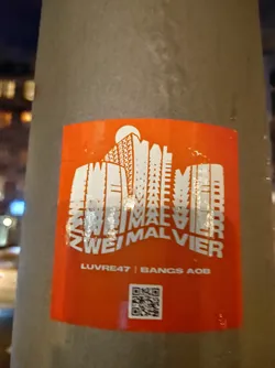An orange sticker with a stylized cityscape design featuring the text 'ZWEIMAL VIER' repeated and layered to create the building forms. The bottom includes the text 'LUVRE47 | BANGS AOB' and a QR code. 
