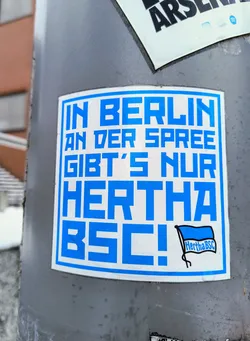 Street sticker A blue and white sticker with the text "In Berlin an der Spree gibt's nur Hertha BSC!" and a small Hertha BSC logo. The text is in German and translates to: "In Berlin on the Spree there is only Hertha BSC!". It's likely a sticker from a Hertha BSC fan.