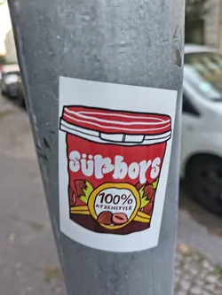 Street sticker A rectangular sticker depicting a red hazelnut spread container. It features the stylized white text 'Süßboys' and a yellow emblem reading '100% ATZENSTYLE' decorated with hazelnuts.